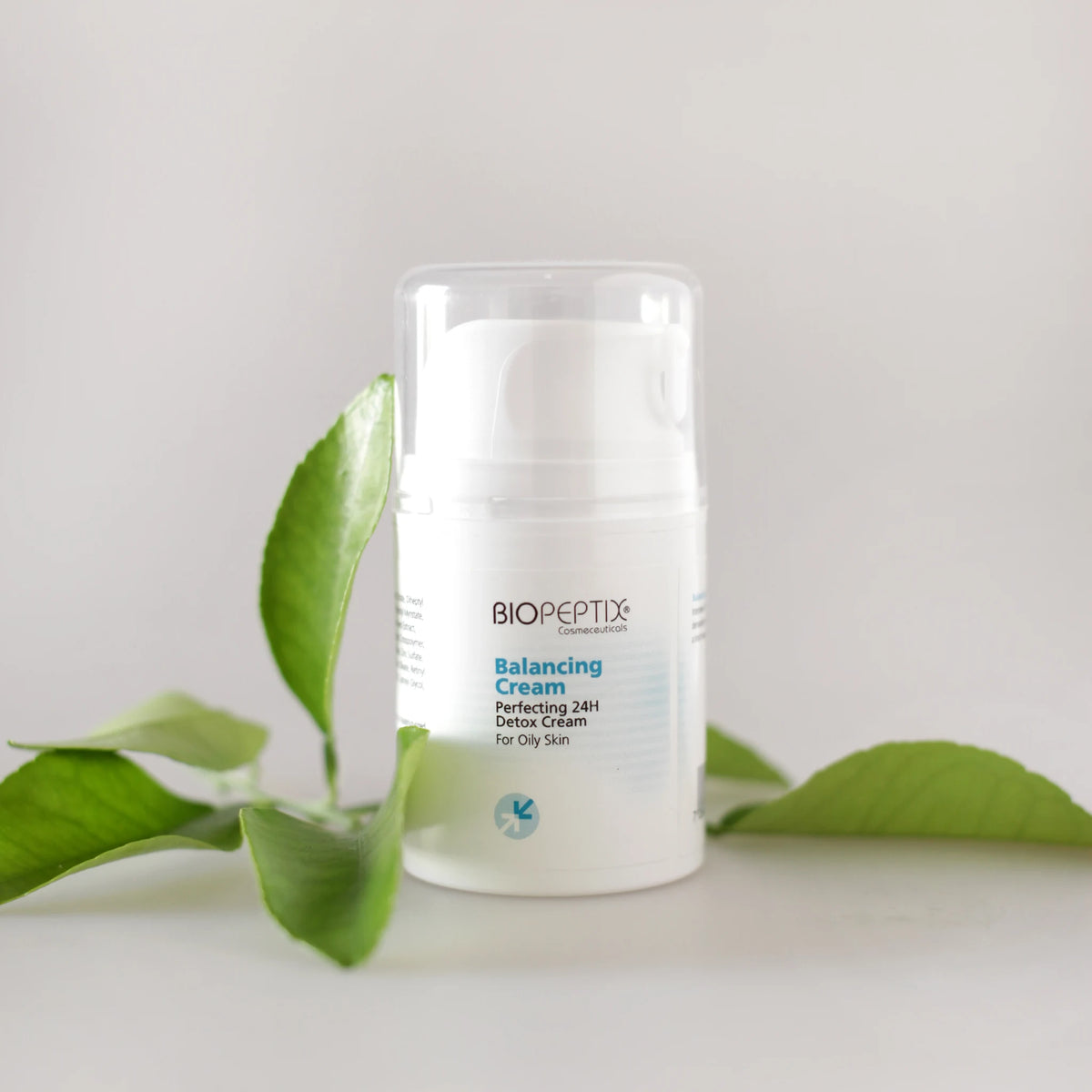 בלאנסינג קרם של Biopeptix, בקבוק איירלס לצד ענף עלים ירוקים